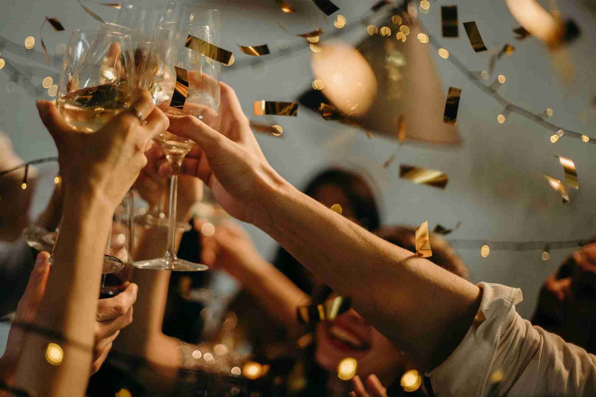 People raising glasses in a toast with confetti falling around