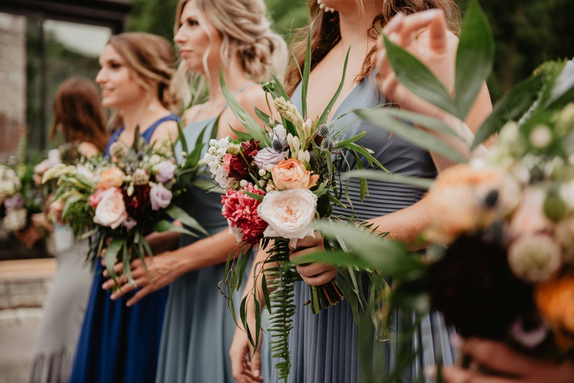 Bridesmaids in matching dresses holding colorful flower bouquets