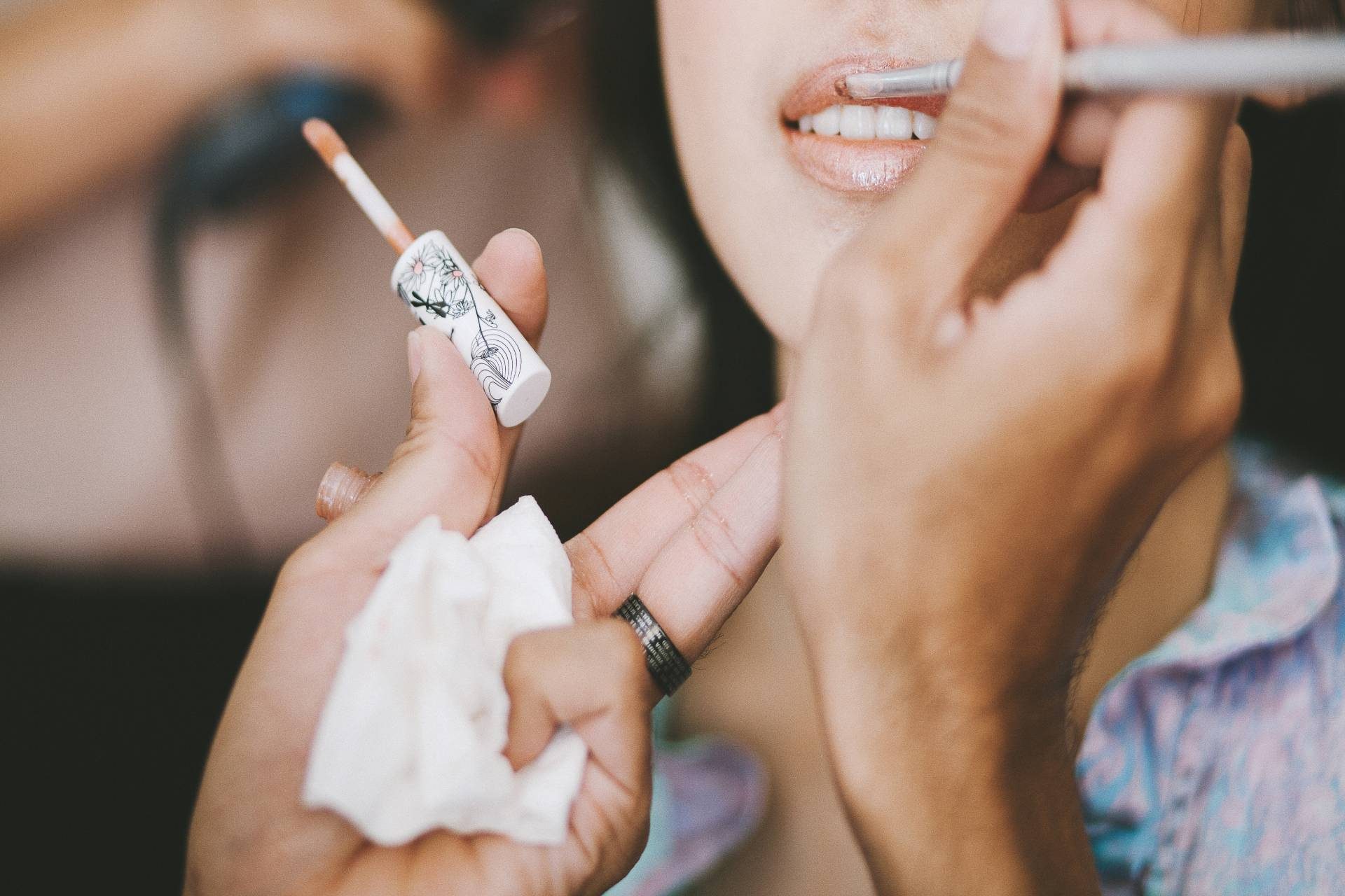 Close-up of a makeup artist applying lip gloss to a woman’s lips