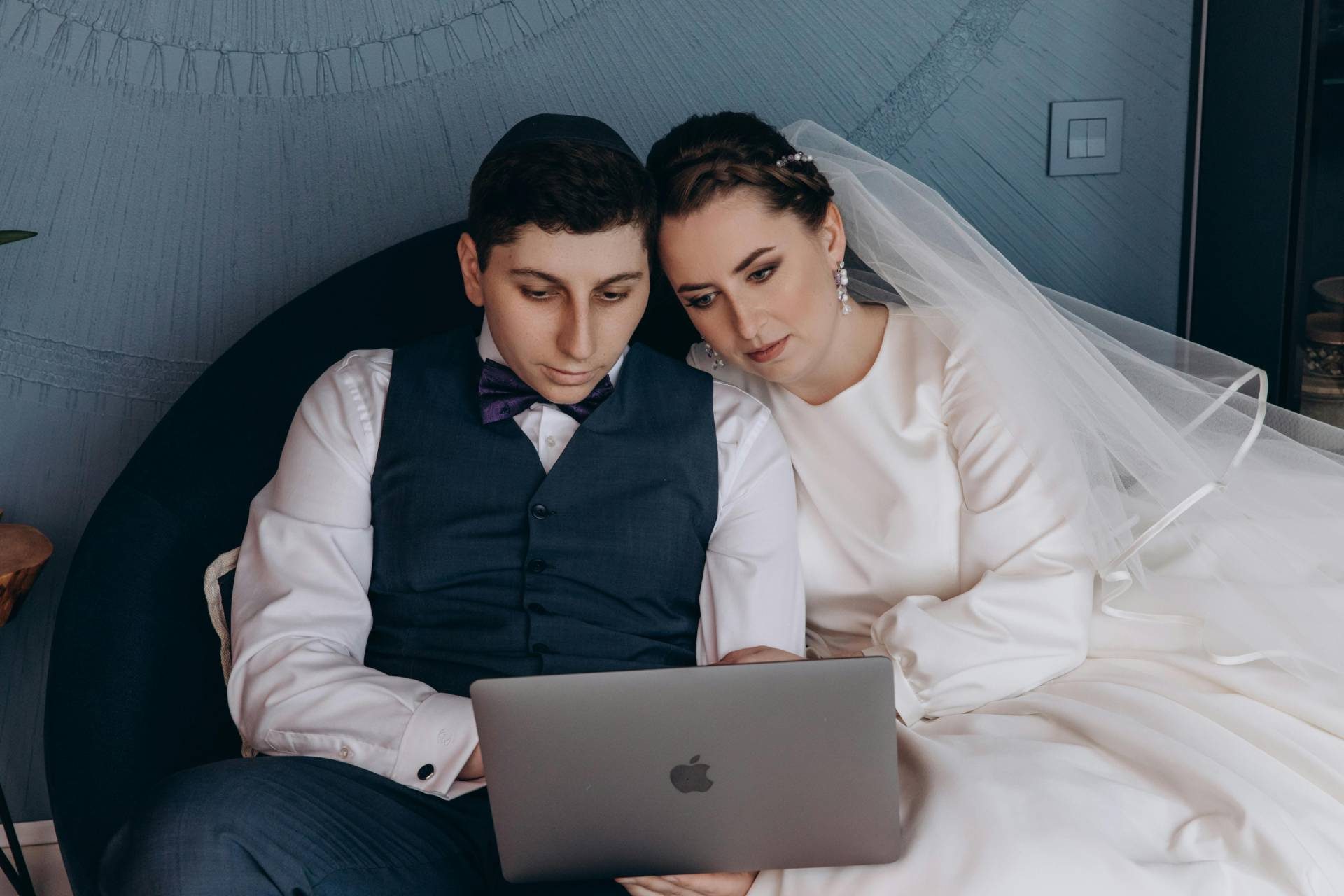 Bride and groom sitting together looking at a laptop while planning their wedding