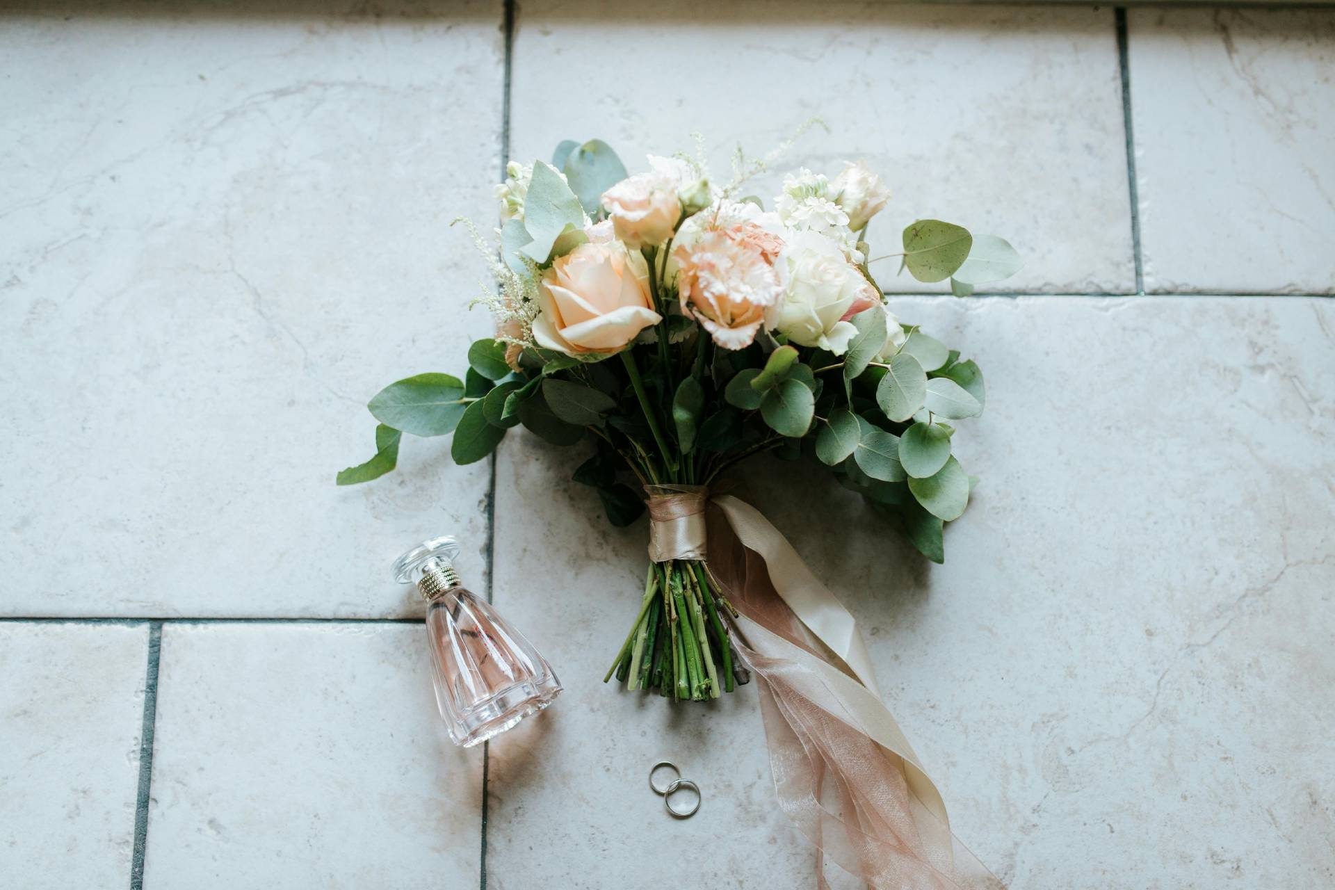 Wedding bouquet and perfume bottle on tiled floor
