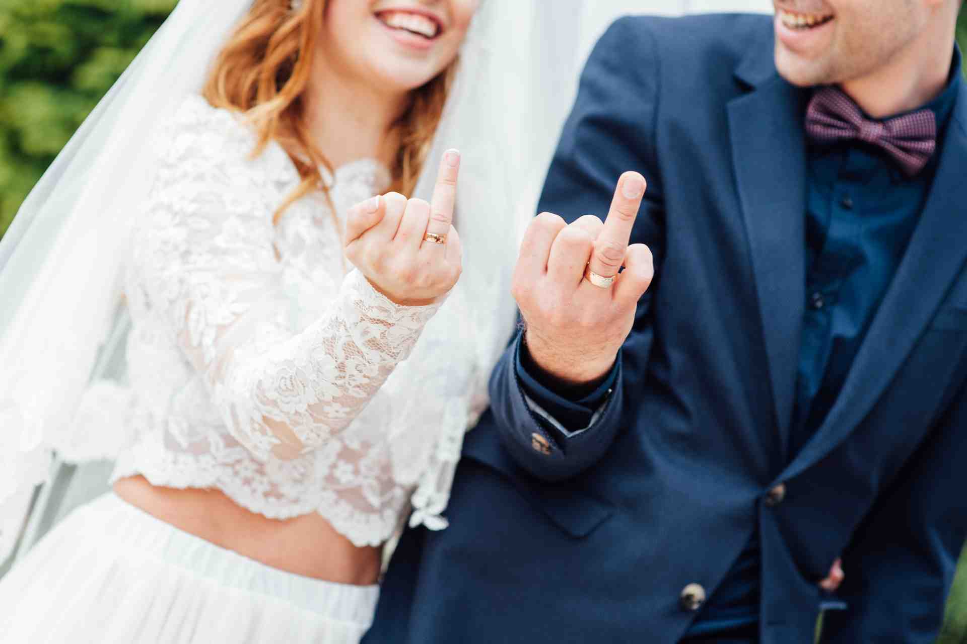 Bride and groom showing their wedding rings while laughing